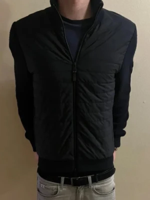 J.Lindeberg hybrid cardigan - Nypris 5000, storlek M men passar också Stor S. Modellen är 178 och väger 63 kilo. Endast 999.