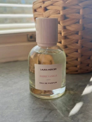 Laura Mercier Ambre Vanille EdP - En elegant parfym från Laura Mercier med doften Ambre Vanille. Flaskan är rund och genomskinlig med en ljusbeige etikett och matchande lock. Innehållet är ljust gult och flaskan har en stilren, minimalistisk design som känns lyxig och modern. Endast testad. 50ml