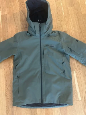 Grön skid/vinterjacka från Peak Performance - Grön vinterjacka från Peak Performance. Färgen heter Pine needle. Den är sparsamt använd, endast 1 vecka i fjällen. 