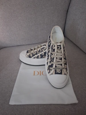 Dior Walk'n'Dior Platform sneakers - Snygga låga sneakers från Dior med klassiskt blått och vitt Oblique-mönster. Skorna har vita snören, gummisula och detaljer med Christian Dior-logga både fram och bak. Tillverkade i canvasmaterial som ger en exklusiv känsla.