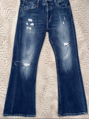 Blå slitna jeans från Jack & Jones - Säljer ett par blå jeans från Jack & Jones med slitningar och hål på benen. Jeansen har en rak passform och klassisk femficksdesign. Perfekta för en avslappnad och trendig look. Materialet är denim i bomull.