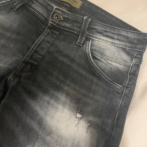 Blå jeans från Jack & Jones med slitningar  - Snygga blå jeans från Jack & Jones med en slitningar, modellen är Slim Glenn. Väldigt mörk blå färg, unika. Använda men nyskick!