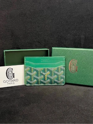 Grön korthållare  - Stilren grön korthållare  med klassiskt mönster och logotyp framtill. Tillverkad i läder med flera kortfack och detaljer i vitt och gult. Perfekt för dig som vill ha en exklusiv accessoar med ikonisk design.