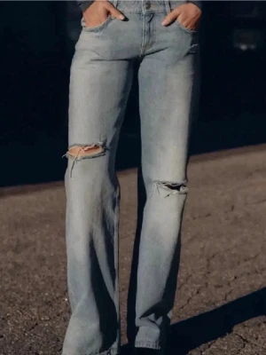 Ljusblå low waist jeans - Ljusblå jeans från Zara med low waist och slitningar i storlek 36