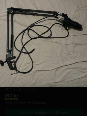Svart mikrofon med stativarm - Säljer en svart mikrofon med tillhörande stativarm och kabel. Perfekt för streaming, podd eller gaming. Armen är i metall och mikrofonen är kompakt och smidig att montera på skrivbordet.