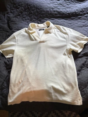 Vit piké t-shirt med krage - Snygg vit piké t-shirt med klassisk krage och v-ringning från Jack and Jones, T-shirten har korta ärmar och är tillverkad i ett mjukt bomullsmaterial. Perfekt för en clean och stilren look.