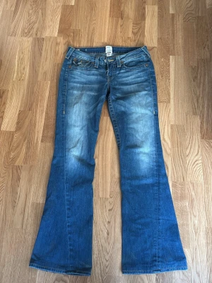 Blå bootcut jeans från True Religion - Superfina jeans från true religion. Köpta på vinted men bara använda några få gånger på grund av att de inte passade så bra🥰de har två hål på insidan av midjan ( bild 4 ) där man dragit ett skärp igenom men inget som syns från utsidan. De är lite långa på mig som är ca 167 cm så de kan absolut passa nån lite längre🤗