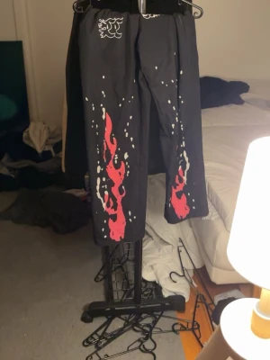 Gymbyxor - Svarta mjukisbyxor med coolt rödflammigt tryck längs benen och vitt mönster upptill. Byxorna har avslappnad passform och resår i midjan. Perfekta för en streetwear-look och riktigt bekväma att ha på sig. otroligt sköna 