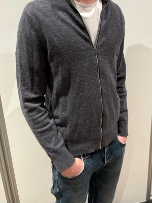 Riley fullzip - Grå fullzip från Riley i 100% merino ull. Ljuset gör att den ser lite nopprig ut men det är den inte. Storlek M han på bilden är 181 cm. Nypris 1200, mycket bra skick. 