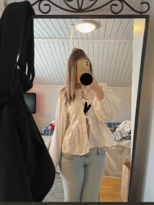 Vit blus med knytning fram - Säljer en vit blus med voluminösa ärmar och knytning framtill. Blusen har en lös passform och är tillverkad i ett tunt, krispigt tyg som ger en avslappnad look. Perfekt att styla med jeans eller kjol för en trendig outfit.