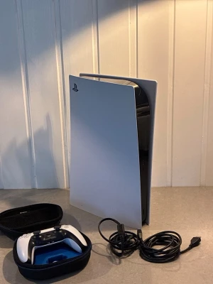 PlayStation 5 med handkontroll och kablar - PlayStation 5 konsol i vit och svart design från Sony. Medföljer en vit och svart DualSense-handkontroll, laddningskabel, HDMI-kabel och en svart förvaringsväska till kontrollen. Priset är inte hugget i sten så kom gärna med förslag👍