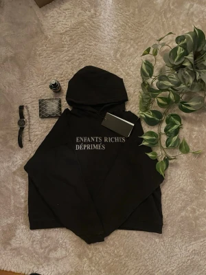 Enfants Riches Déprimés hoodie  - Svart hoodie från Enfants Riches Déprimés med vit text på bröstet. Klassisk passform med huva och känguruficka framtill. Mjuk bomullskänsla och avslappnad stil, perfekt för dig som gillar streetwear och exklusiva märken.
