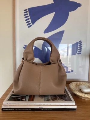 Beige/Taupe handväska  - Använd fåtal gånger. Axelband medföljer, se bild. Köpt i en butik i Nice. 