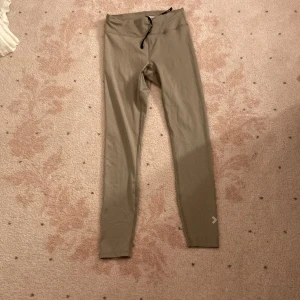 Beige leggings  - Säljer ett par beige leggings med smal passform och dragsko i midjan. De är långa och har en enkel, stilren design utan synliga loggor eller mönster. Perfekta för en avslappnad och bekväm look.