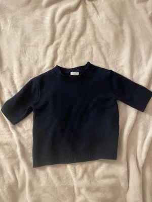 Mörkblå stickad topp från Kappahl - Snygg mörkblå stickad topp från Kappahl med korta ärmar och rund halsringning. Tröjan är lite nopprig och ganska använd.