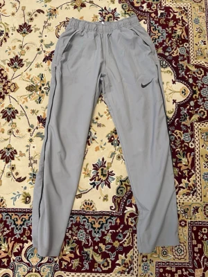 Gråa mjukisbyxor från Nike - Säljer ett par gråa mjukisbyxor från Nike med elastisk midja och sidofickor. Äkta träningbyxor köpt från nike