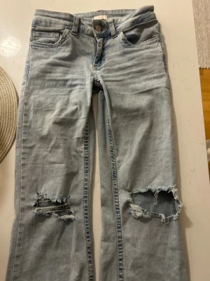 Jeans från Nelly st 34 - Supersnygga jeans med hål på knäna, snyggt slitna (från butik) och jättesköna. Lite slitna i nederkant som de ska vara, snygga fickor bak se bild. 