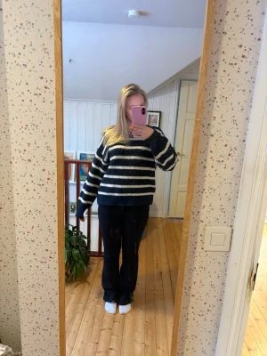 Svarta bootcut jeans med låg midja - Säljer ett par svarta jeans med bootcut passform och låg midja. Jeansen har klassisk femficksdesign och stängs med knapp och dragkedja. Perfekta till vardags och lätta att matcha med olika stilar.