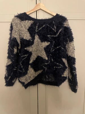 Stickad tröja med stjärnor - Säljer en fluffig stickad tröja i mörkblått och vitt med stora stjärnmönster. står storlek m/L men skulle säga den är xs då jag bör xs annars.