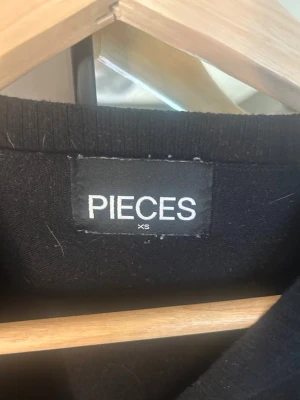 Svartvit randig stickad tröja PIECES - Säljer en svart stickad tröja från PIECES i storlek XS med vita horisontella ränder. Tröjan har rund halsringning, långa ärmar och en något croppad passform. Aldrig använd 