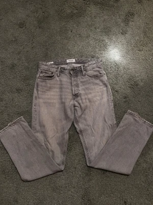 Grå loose fit jeans Jack & Jones - Snygga grå jeans i loose fit-modell från Jack & Jones.  Jeansen har klassisk femficksdesign, raka ben och hög midja. Perfekta för en avslappnad och trendig stil. Tillverkade i denim med en tvättad finish för en cool look.