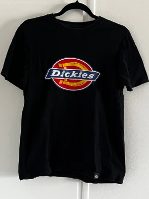 Svart Dickies t-shirt med logga XS - Svart t-shirt från Dickies med stor färgglad logga på bröstet. Klassisk passform med rund hals och korta ärmar. Tillverkad i  bomull och har en liten Dickies-tag nertill på framsidan. 