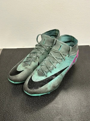 Nike Mercurial  - Nike Mercurial fotbollsskor i turkos med svarta och rosa inslag. Skorna har hög krage, snörning och en lätt, slitstark ovandel i syntetmaterial. Orginal påsen tillkommer. Storlek 43⭐️