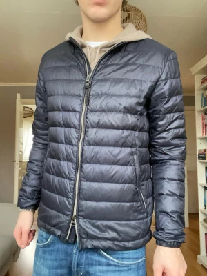 Woolrich cardigan jacka – strl S - Stilren quiltad cardigan/jacka från Woolrich. Perfekt som mellanlager eller lätt jacka. Väldigt hög kvalitet och tidlös design.  Passar både casual och mer uppklädda outfits.  Öppen för bud! Skick: Mycket bra skick Storlek: S Färg: Grå/blå ton  Pris: 799kr