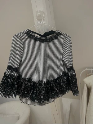Randig blus med spetsdetaljer - Jätte snygg  blus från Zara med spetsdetaljer. Blusen har trekvartsärm och en dekorativ spetskant vid halsen. V-ringad i ryggen och knyts med en rosett. Materialet känns lätt och luftigt, perfekt för en trendig look. Säljer då den tyvärr aldrig kommer till användning, toppen skick💗