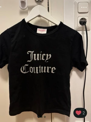 Ny Svart Juicy Couture t-shirt - Snygg svart t-shirt från Juicy Couture med klassisk logga i vitt framtill. T-shirten har rund halsringning och korta ärmar. Perfekt för dig som gillar streetstyle och vill ha en enkel men ikonisk look. Nästan helt ny, köptes i december och har bara använts 3 gånger hemma.