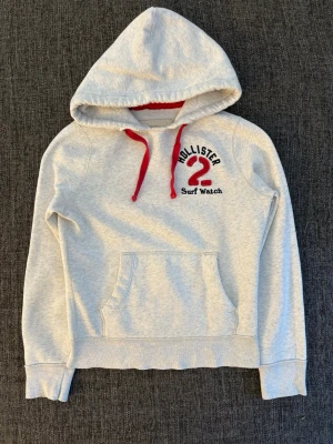 Hollister hoodie - sällsynt  - Eftertraktad Hollister hoodie i grå färg, tidlös modell i fint skick. Perfekt för vardag och casual outfits.  • Storlek: S • Skick: Väldigt bra • Färg: Grå/vit • Material: Mjukt, bekvämt och välbevarat  Varför den är unik: – Klassisk Hollister-design som alltid håller – Svår att hitta i detta skick – Perfekt basic hoodie som funkar året runt  Skickas snabbt och tryggt 📦 inom 24h 