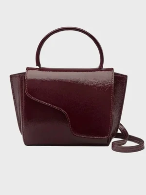Vinröd ATP väska  - Snygg vinröd handväska i glansigt lackat läder med unik asymmetrisk lockdesign. Väskan har både handtag och avtagbar axelrem med guldfärgade detaljer. Perfekt för dig som vill ha en trendig accessoar med modern form, nypris 4099. 