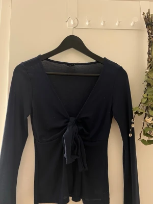 Topp gina tricot  - Snygg marinblå långärmad topp från Gina tricot med v ringing och knyt framtill.