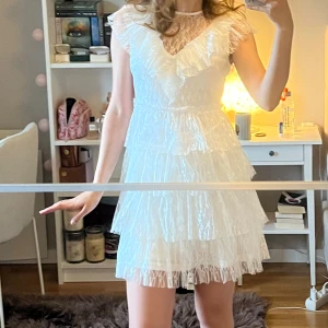 Supersöt studentklänning med volang - Supersöt vit studentklänning från Bubbleroom med flera lager volanger och transparent spets upptill. Nypris är 899kr. Använd 1 gång, på min studentdag☺️💕 Storleken på lappen är XS men skulle säga att den är mer åt S hållet eller 36.