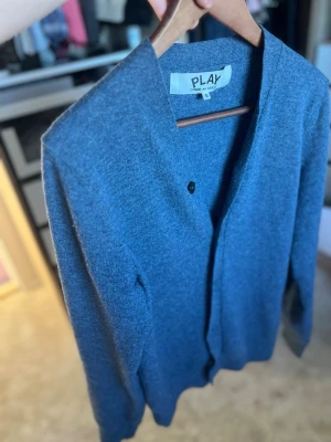 Blå cardigan från Comme des Garçons - En snygg och stilren blå cardigan från Comme des Garçons. Passar perfekt med en T-shirt eller skjorta. Nypris:5100 Vid snabb affär kan priset diskuteras! Kom med bud!