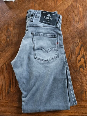 Replay Anbass - Snygga grå slim fit jeans från Replay, modell Anbass. Klassisk femficksdesign med diskret logga på bakfickan. Perfekta för dig som gillar en smalare passform och stilren vibe. W30 L32.