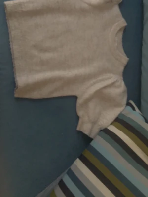 Ljusgrå stickad tröja Gina Tricot - Ljusgrå stickad tröja från Gina Tricot med rund halsringning och ribbade muddar. Tröjan har en enkel och stilren design, perfekt för lager-på-lager och passar till många olika outfits.