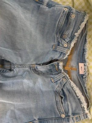 Nelly lågmidjade Ljusblå  bootcut jeans  - Säljer ett par lågmidjade ljusblå jeans från Nelly. Obs! Klippta i längd passar dig som är petite >162