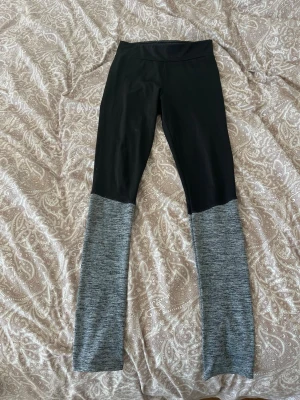 Svarta och gråmelerade leggings - Snygga leggings med svart överdel och grå ben. Hög midja och stretchigt material som sitter skönt på kroppen. Perfekta för en avslappnad stil eller till träning. Inget synligt märke.