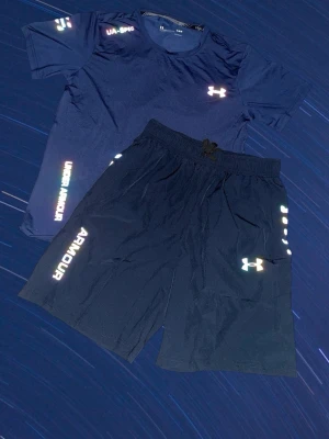 Under Armour set - mörkblå - Snyggt blått träningsset från Under Armour med t-shirt och shorts. Båda plaggen är reflektiva. Mörkblå storlek m OBS!! Köp inom 48 timmar få 149kr rabatt!!