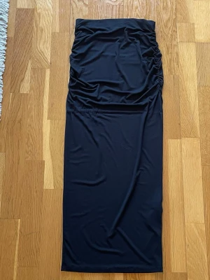 Svart långkjol från Gina Tricot - Svart långkjol från Gina Tricot med tight passform och rynkade detaljer upptill på ena sidan💗