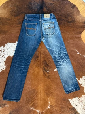 Nudie jeans SharpBengt DryOrangeSelvage - Tjena! Säljer dessa nudies I modellen sharpbengt dryorangeselvage som tillverkades under 2010talet, W29/L32, Midja-40,5cm/ Längd-104cm/ benöppning-18cm, Byxa 2 är enbart med som ett exempel på hur dessa jeans åldras, det är exakt samma modell bara att ena paret är hårt använt, hör av dig vid funderingar!🙌