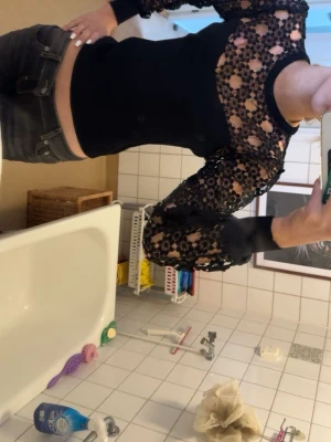 Svart topp med spetsärmar och blommönster - Trendig svart topp med långa ärmar i transparent spets och blommigt mönster. Kroppsdelen är tight och enfärgad medan ärmarna har en snygg volym. Perfekt för dig som vill sticka ut med en cool detalj.