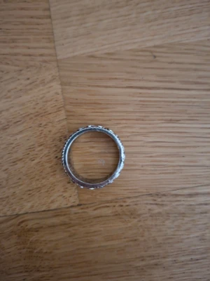 Silverfärgad ring med kedjemönster - Säljer en stilren silverfärgad ring med ett detaljerat kedjemönster runt hela ringen. Ringen har en något bredare design och fina kanter med små räfflor. Perfekt för dig som gillar accessoarer med lite edge och unik känsla.