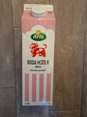 Arla rosa mjölkdryck jordgubb - En 1-liters förpackning rosa mjölkdryck från Arla med smak av jordgubb. Kartongen är vit och rosa med en röd ko och grönt Arla-märke på framsidan. Perfekt för dig som gillar smaksatt mjölk och vill testa något annorlunda.