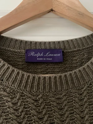 Ralph Lauren Purple Label - Snygg olivgrön stickad tröja från Ralph Lauren purple label, tillverkad i Italien. Tröjan har ett klassiskt fiskbensmönster, rund halsringning och ribbade muddar vid ärmslut och nederkant. Perfekt för dig som gillar stilrena och tidlösa plagg. Vid frågor skicka ett mess. 