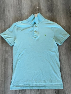 Polo Ralph Lauren piké - Snygg ljusblå piké med ett grönt broderat Polo Ralph Lauren märke. Väldigt bra skick. Storlek S