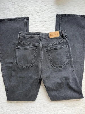 Grå raka jeans från NA-KD - Snygga grå jeans från NA-KD med raka/vida ben. Jeansen har hög midja. Perfekta för en trendig look. Jag skickar inte fler bilder då dem ligger i flyttlåda.