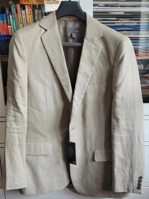 Beige linnékavaj från hm - Stilren beige kavaj i linne från Hm. Klassisk passform med två framfickor, bröstficka och knappar vid ärmslut. Perfekt för en avslappnad men ändå dressad look. Tunt foder och snyggt snitt gör den lätt att bära. Nypris 999 kr 
