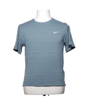 Blå Nike t-shirt med diskret struktur - Snygg blå t-shirt från Nike med diskret strukturerat tyg och klassisk rund halsringning. T-shirten har korta ärmar och en liten vit Nike-logga på bröstet. Perfekt för en sportig och avslappnad stil.